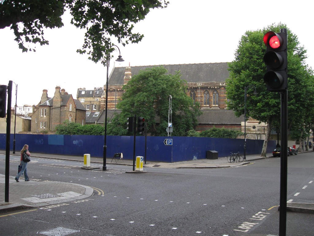 The corner of Queen's Gate and Harrington Road in Kensington - with an unoccupied stretch of land surrounded by a blue hoarding.